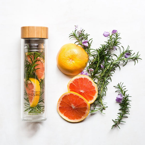 Glass Fressko flask filled with water infusion, grapefruit and rosemary surrounding