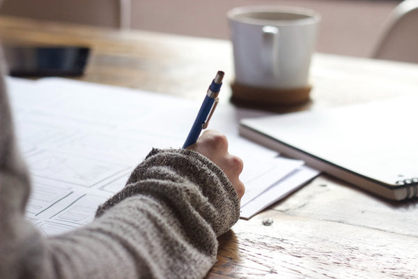 woman writing in diary with coffee in background