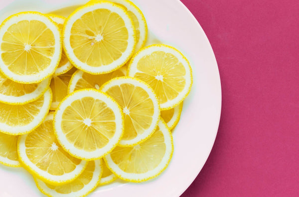 Lemon on a white plate with pink background